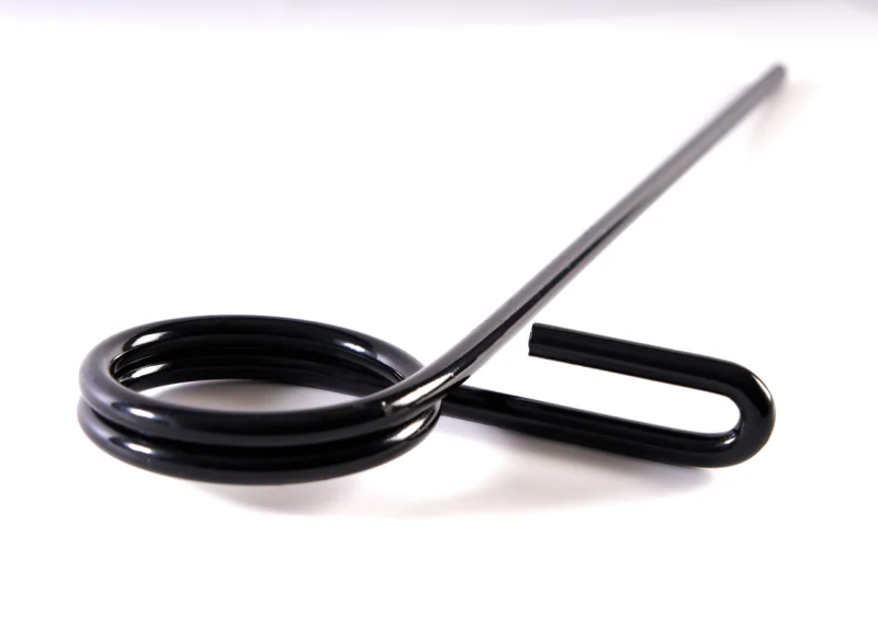 Muelle de torsión de acero inoxidable sobre fondo blanco, con cuerpo helicoidal denso y dos brazos largos que presentan una angulación o codo para facilitar el anclaje mecánico.